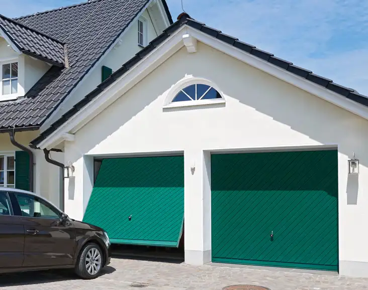 Große Garage mit zwei grünen Sektionaltoren von Almtor