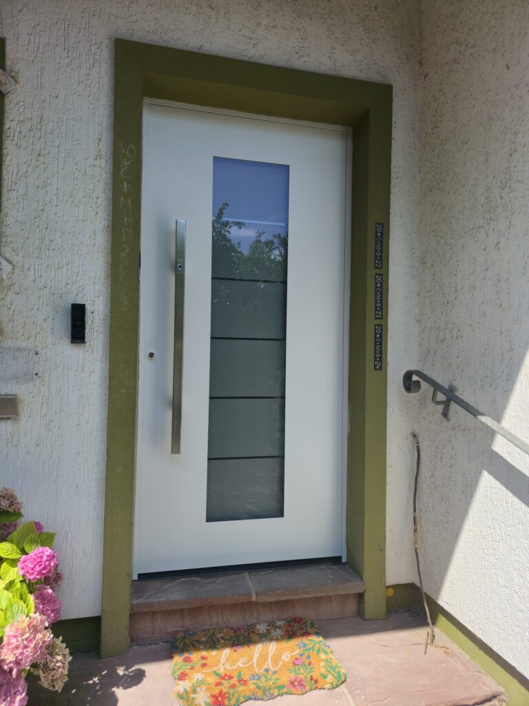 Weiße Haustür mit mittigem Milchglaseinsatz für moderne Wohnhäuser